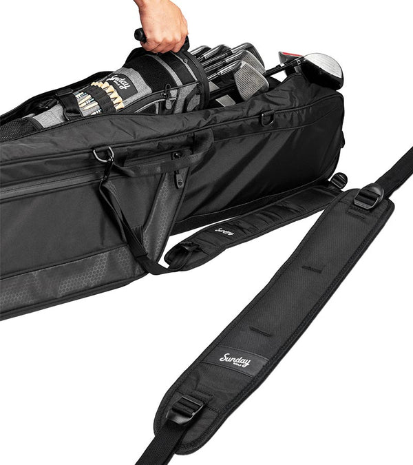 Sunday Golf The Mule Golf Travel Bag in black - partial view showing a hand lefting out a golf bag filled with clubs. In the foreg round is the padded carry strap.