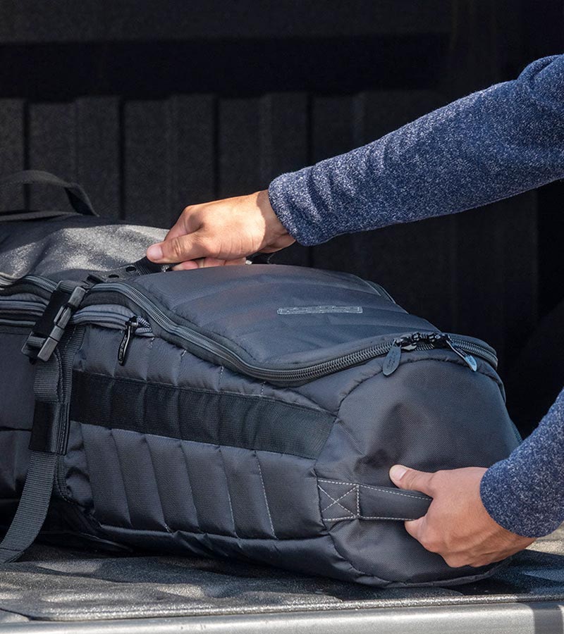 BAG BOY  ZTF Travel Bag Cover in black/charcoal being placed in a car trunk.