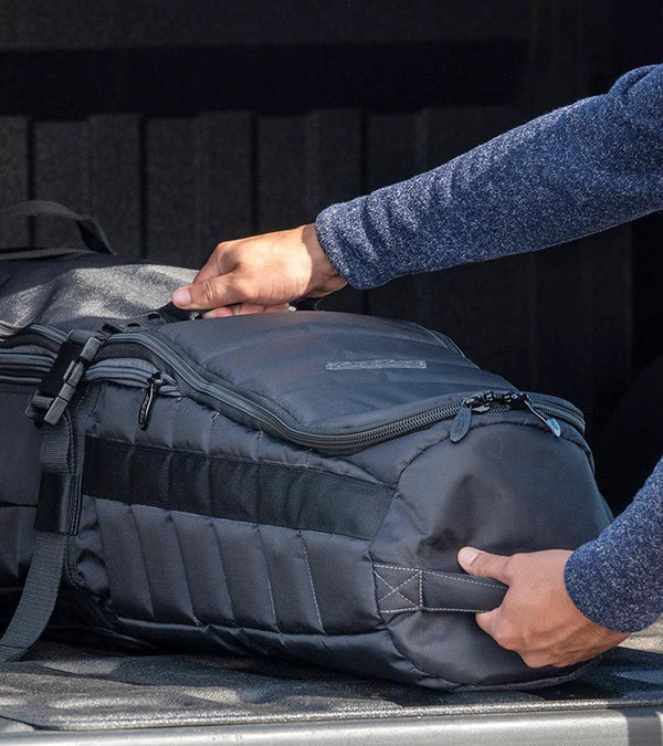 BAG BOY  ZTF Travel Bag Cover in black/charcoal being placed in a car trunk.