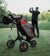 BagBoy Chiller Cart Golf Bag in Charcoal/Red/Black -on push cart with male golfer in background finishing a swng
