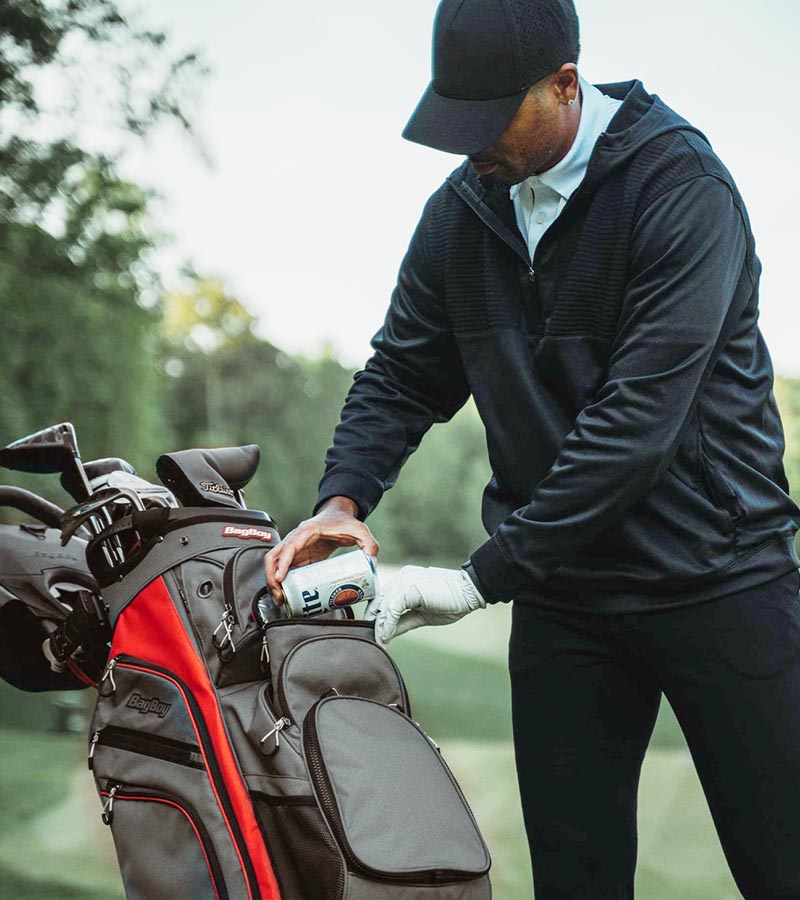 BagBoy Chiller Cart Golf Bag n Charcoal/Red/Black - male golfer getting a can from cooler pouch pocket
