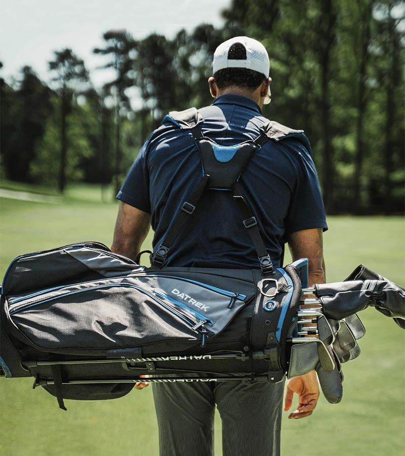 Golfer carrying on back the Datrek Go Lite Hybrid Golf Stand Bag in Black/Charcoal/Royal