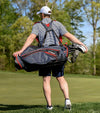 Golfer carrying on back the Datrek Go Lite Hybrid Golf Stand Bag in Charcoal/Black/Red