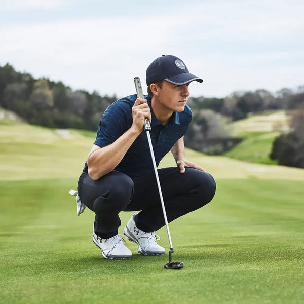Golfer with putter lining up to putt on green