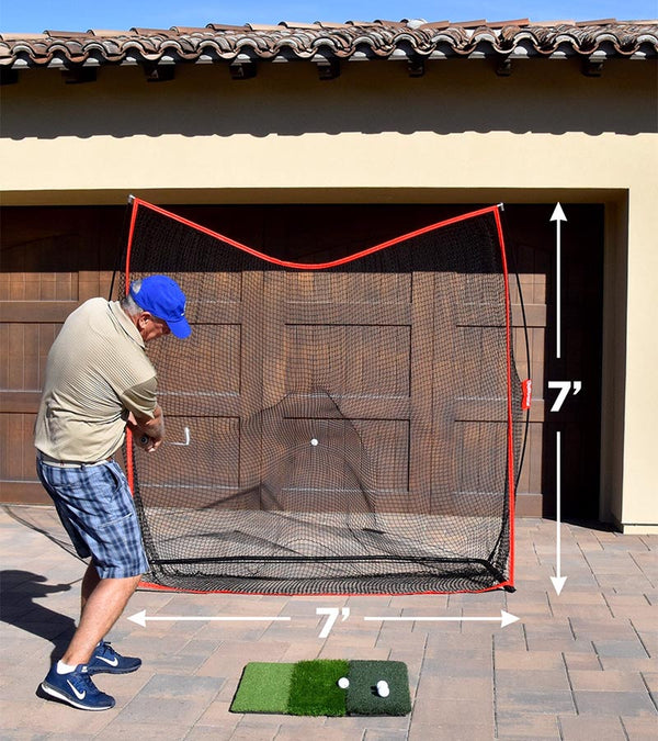 GoSports Golf Practice Hitting Net 7 Ft X 7 Ft - Golfer practicing in driveway with wood garage door behind the net with 7'x7'dimensions shown with white arrows