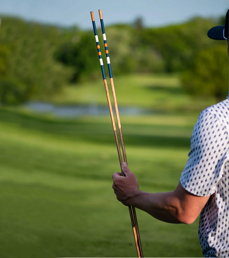 Hazy Golf Alignment Sticks - The Volunteer - pair of sticks held by a gplfer - golf fairway in the background