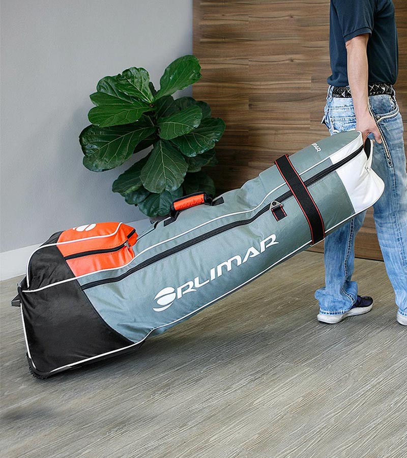 Orlimar 1680D Super Duty Deluxe Wheeled Golf Travel Cover in grey with red and black accents - loaded and being pulled by man