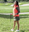 Pirdie Twilight Golf Vest in Hot Coral with model standing on the fairway with a club