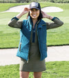 Pirdie Twilight Golf Vest in Dark Teal with accents in Olive Green for the zipper -front view on partial model standing on a golf course