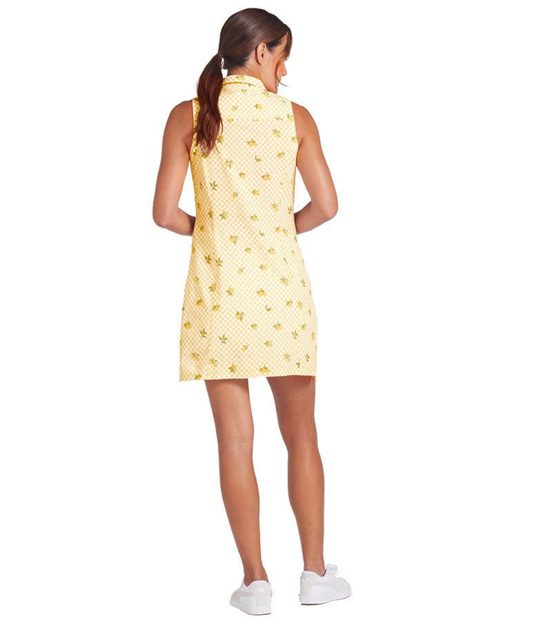 Puma Lemons Woven Womens Golf Dress- model-back view in Sunny Yellow, an allover lemon print on a cheerful yellow-and-white checkered background.