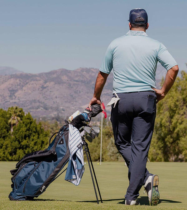 Sunday Golf Ryder Full Size Stand Golf Bag in Navy Blue – Male golfer standing with back to viewer on a golf course.