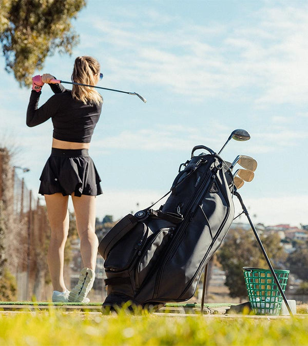Sunday Golf Ryder S-Class Full Size Stand Golf Bag in black Vegan Leather – female golfer at practice range