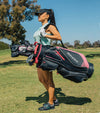 Women golder on the fairwat carrying the Aspire PRO-X Complete Set Stand Bag with 10 clubs and headcovers in black with pink and white accents