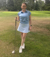 Birdie & Ace Lily Womens Golf Polo in Aura Blue-  model holding a driver in the fairway