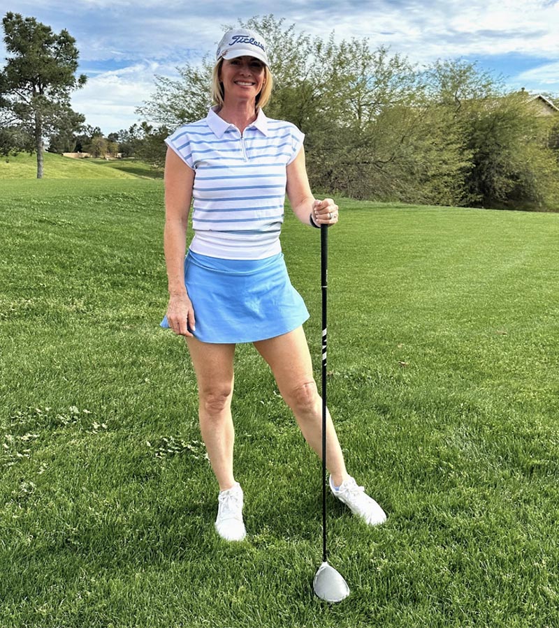 Birdie & Ace Lily Womens Golf Polo in Aura Blue Stripe-  model holding a driver on the fairway