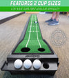 GoSports Pure Putt 9 Ft Indoor Putting Green Mat - closeup of incline end with 2 cup sizes, 3 golf balls, and a partial person in the background putting.