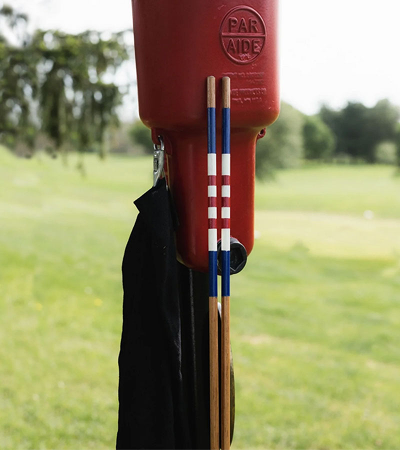 HazyGolf Alignment Sticks –  American Glory - pair vertical leaning against a Par Aid on a golf course