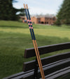 Hazy Golf Alignment Sticks – The Brook -closeup of a pair of sticks leaning against a bench with a golf course in the background