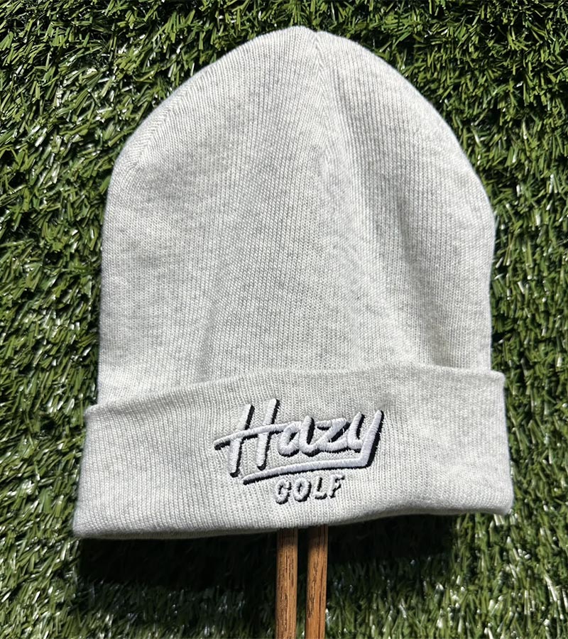 Hazy Golf Portland Logo Cuffed Beanies- front view with logo on cuff- in White Heather on grass back ground