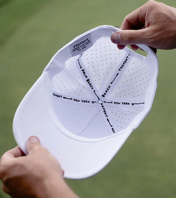 Hazy Golf’s Hazy X Tremont Dune Hat-in White inside view. Hat held by hands of golfer against an out-of-focus green background