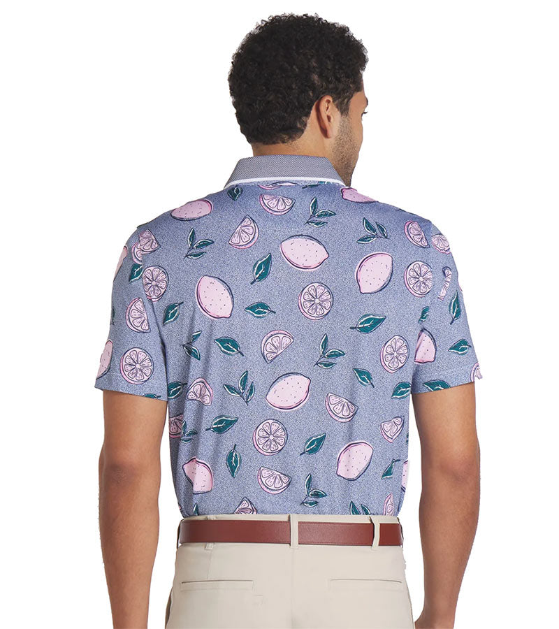 Puma Mens AP Pink Lemonade Polo Shirt Model -back in Deep Navy is a fun conversational print with leaves and tossed full and sliced lemons pieces floating on a tiny dot background. The collar is a solid coordinating color with white piping at the edges with a related light color for the inner collar and the 3 button inner placket.