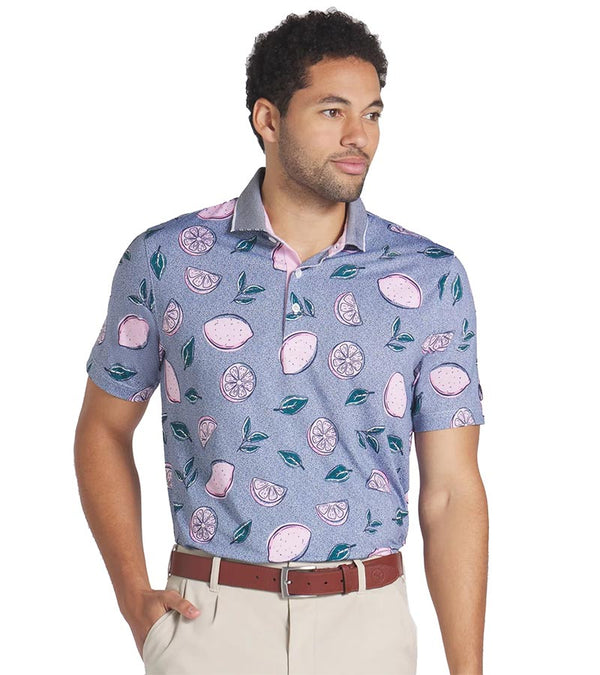 Puma Mens AP Pink Lemonade Polo Shirt Model Front in Deep Navy is a fun conversational print with leaves and tossed full and sliced lemons pieces floating on a tiny dot background. The collar is a solid coordinating color with white piping at the edges with a related light color for the inner collar and the 3 button inner placket.