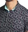 Puma Mens MATTR Paradise Golf Polo closeup of collar in Puma Black / Aquatic  with a with an  all-over pattern floral of little birds of paradise flowers with contrast color accent  inside collar and button placket.