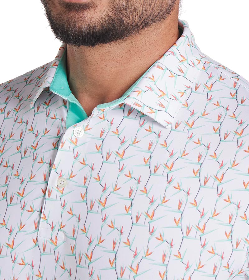 Puma Mens MATTR Paradise Golf Polo closeup of collar in White Glow / Aquatic with a with an  all-over pattern floral of little birds of paradise flowers with contrast color accent  inside collar and button placket.