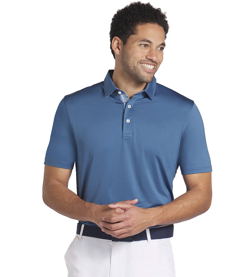 Puma Mens Fair Isle Trim Golf Polo Shirt Model Front in solid Blue Horizon with the geometric print from the Fair Isle Micro golf polo lining the entire inner and under section of the collar and 3 button placket for a distinctive accent to the shirt.