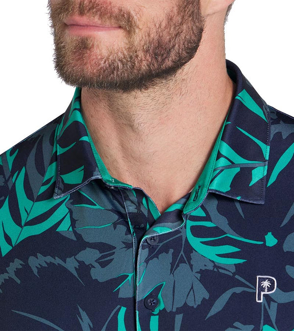 Puma Mens x PTC Palm Glitch closeup of collar in Deep Navy / Sparkling Green has an all over pattern of large lush palm fronds, a classis polo collar, and a 3 button placket.