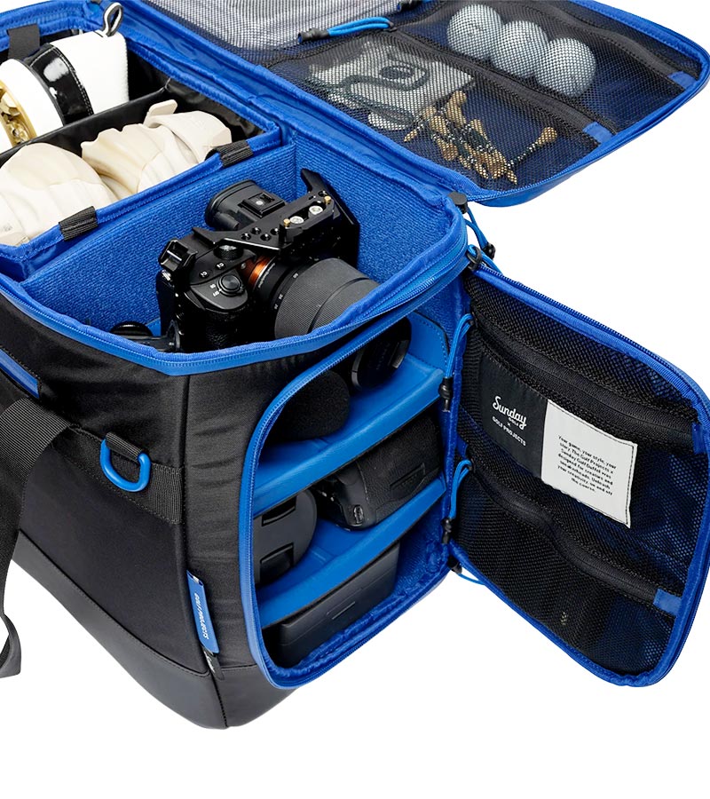 Sunday Golf Creator Duffle Bag in Black with blue accent details shows open  compartments  and pockets for camera  and camera equipment, golf balls, and other items 