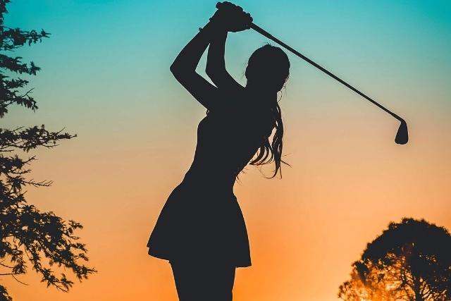 women golfing at sunset