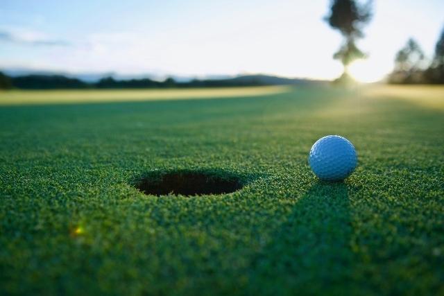 golf ball near hole at sunset