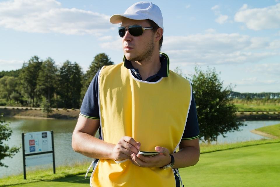 golf caddie standing in yellow vest