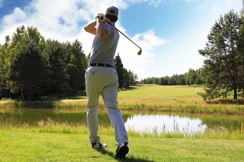 golfer hitting over a pond