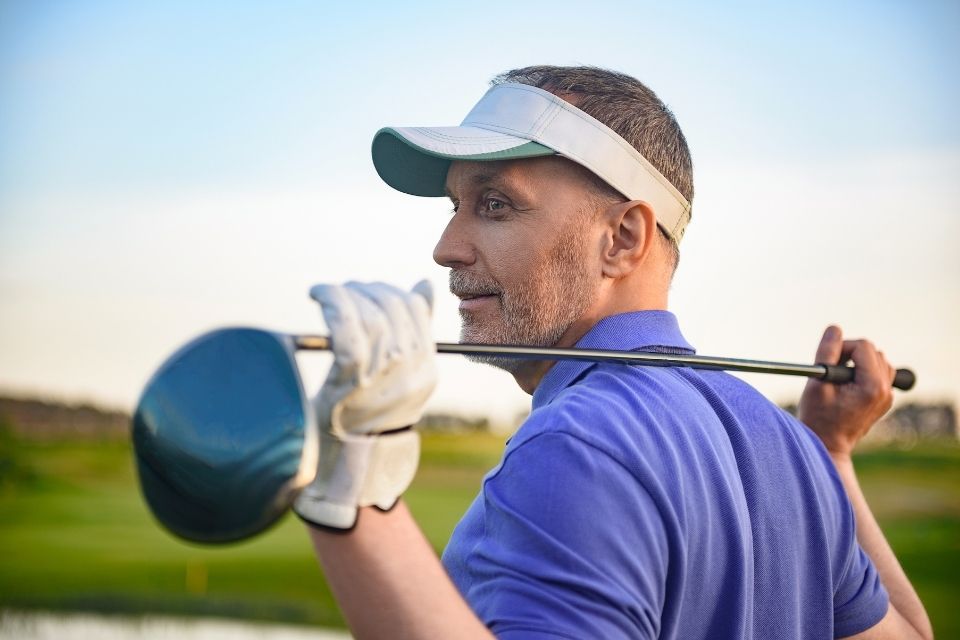 Male golfer measuring driver shaft length on his shoulder