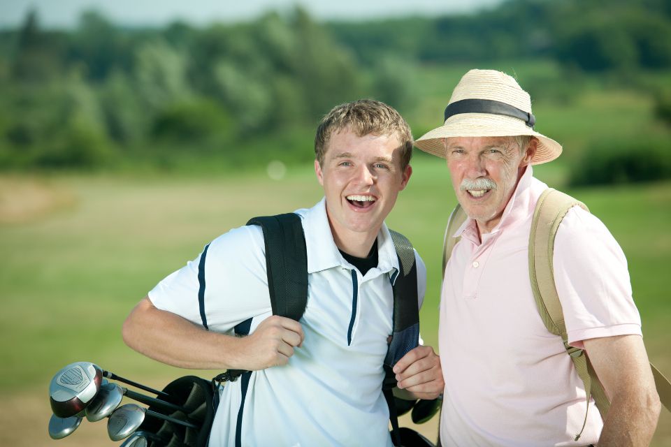 Old man and grandson wearing straw golf hat